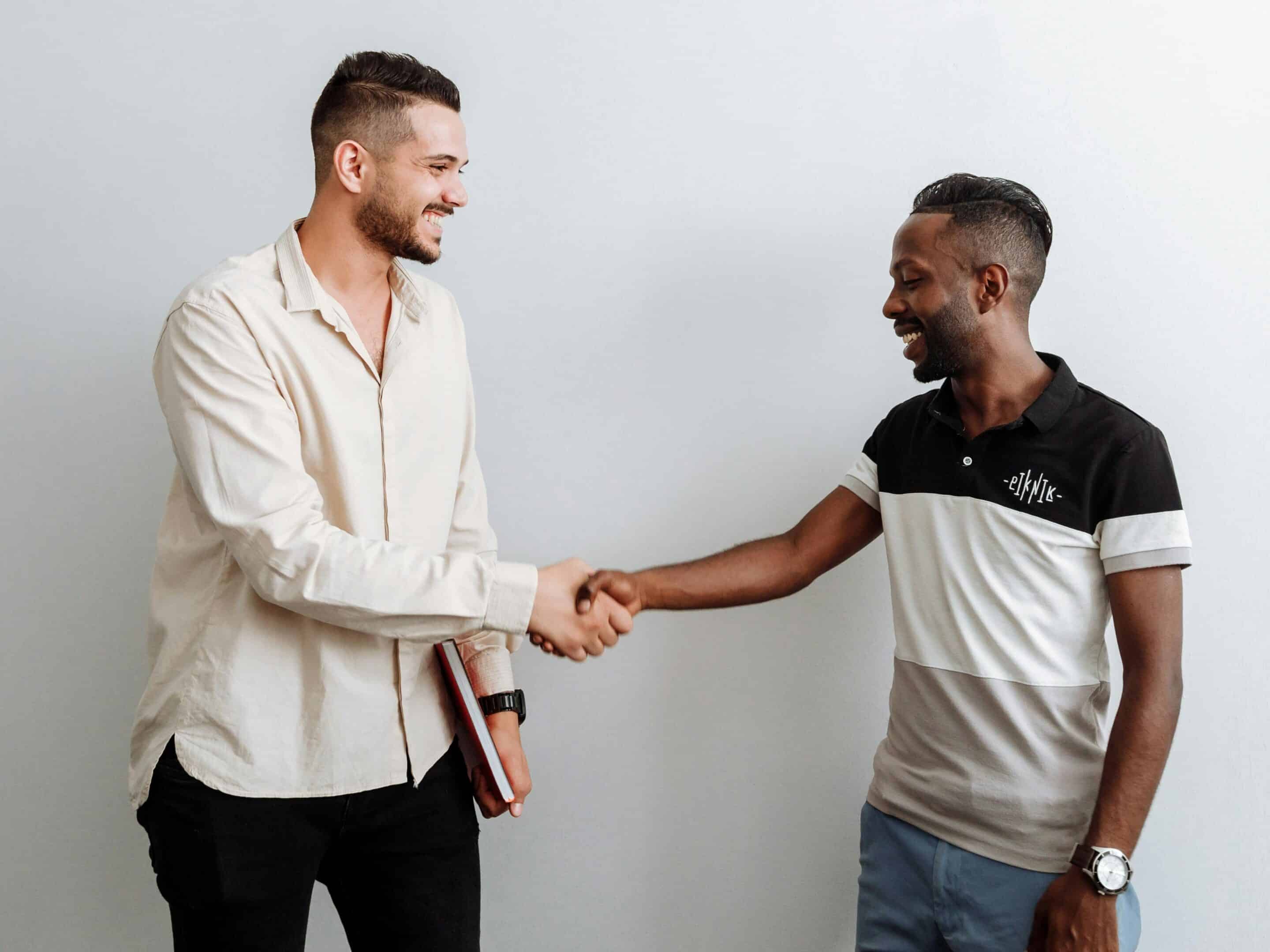 Deux hommes souriants se serrent la main.