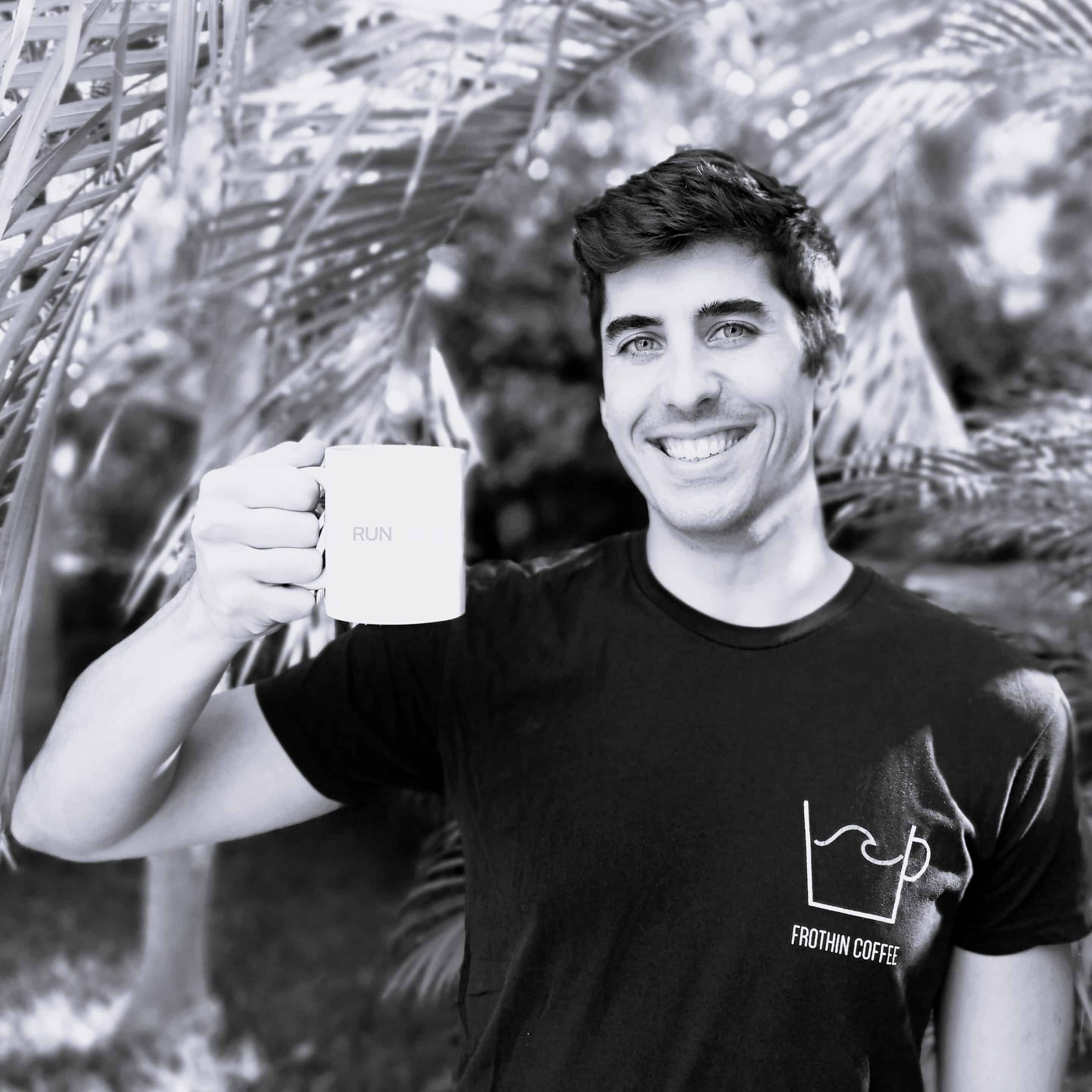 Homme souriant tenant une tasse, vêtement marqué "Frothin Coffee".